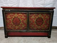 Front view of the chest showing the red and gold lacquer with two doors and circular emblems.