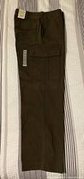 Full side view of one leg showing brown cargo pants with button flap cargo pocket and attached size sticker.