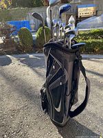 Black Nike golf bag with clubs inserted, side view