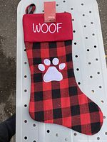 Front of dog Christmas stocking in red and black plaid with white paw print and WOOF embroidered on cuff