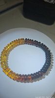Photo of the AAA Baltic amber bracelet showing the chunky round beads arranged in a gradient from yellow to dark brown on a white background.