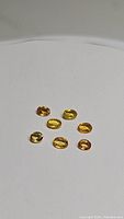 Seven loose natural canary yellow sapphire gemstones in oval cut, showing color and shape variation