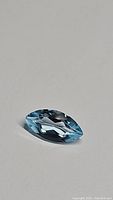 Single natural sky blue topaz marquis cut gemstone on a white background, showing clarity and color.