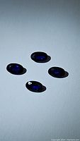 Four oval cut royal blue sapphires arranged on a white background showing their deep blue color and size
