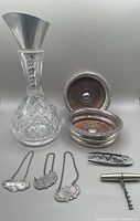 Full lot arranged including Waterford cut crystal wine carafe, silver plate wine funnel, two wine coasters, two cork screws, and three liquor decanter tags on chains.