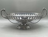 Front view of the silver plated centrepiece bowl with openwork rim, goat head finials, and draped chains.
