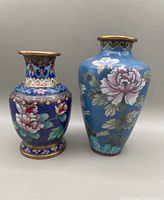 Both cloisonné vases shown side by side, detailed floral and bird enamel designs, brass rims and bases