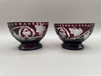 Front view of the two ruby red cut to clear bowls side by side, showing matching decorative patterns and shape.