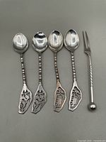 Photo of 4 silver spoons with decorative finials and 1 pickle fork