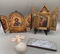 Overview of all four items: holy water font, angel plaque, and two triptychs