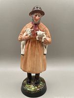 Full front view of the Royal Doulton Lambing Time figurine holding two lambs, showing the overall condition and base details.