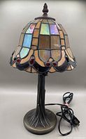 Front view of the lamp showing full stained glass shade and metal base with tree trunk design
