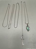 Five chains laid out: two serpentine, one swirl, one spiga, one serpentine with shell and one delicate with key