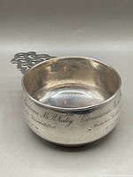 Angled front view showing bowl interior and handle detailing, engraving legible on rim.