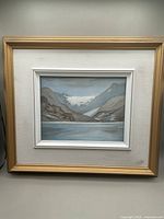 Full view of framed watercolour painting showing Lake Louise in muted tones with linen matte and outer gold-colored frame
