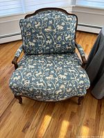 Front view of one bedroom chair showing wooden frame and blue floral upholstery with cushioning on seat and backrest.