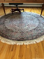 Photo of green and cream round rug with detailed floral and geometric pattern, showing size and condition.