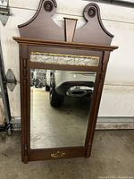 Full view of decorative wooden vanity mirror with carved scroll top and gold detail trim.