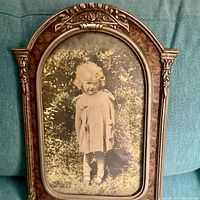 Front full view showing the entire framed photograph of the little girl and the carved wood frame details.