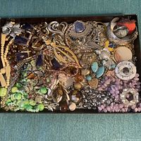 Overhead photo showing the full assortment of vintage jewelry including bracelets, necklaces, earrings, and brooches with stones and various materials.