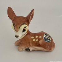 Front and side view of the 1950 Goebel Disney Bambi ceramic figurine showing details of the face and original sticker.