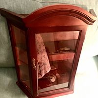 Curio cabinet front and side view showing wood finish and glass panels.