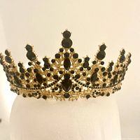 Front view of gold tone tiara adorned with black stones arranged in an intricate symmetrical design.
