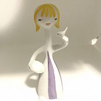 Front view of the Hollohaza porcelain figurine depicting a girl with a bird on her hand, showing the dress and facial features.