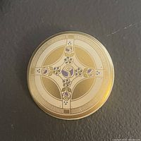 Front view of round enamel brooch with cross and floral pattern in purple and blue on gold tone.