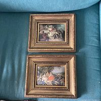 Pair of portrait art pieces on silk fabric within detailed gilt wood frames placed on fabric background. Both frames measure roughly 9x11 inches.