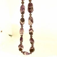 Full view of the amethyst necklace showing the large faceted stones and smaller beads linking them.