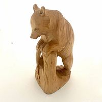 Front angle view of the hand carved wooden bear figurine showing detailed carving on the bear and tree stump.