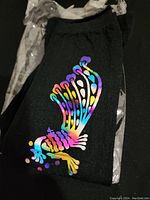 Close-up photo of black sock showing colorful butterfly design in multiple colors including purple, blue, green, yellow, and red.