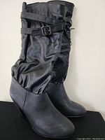 Photo showing full side view of mid-calf black boots with straps and buckles.