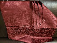 Photo showing four overlapping burgundy fabric samples with floral jacquard pattern and pinked edges.
