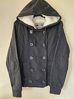 Full front view of the black hoodie showing hood, double-breasted button front, and sherpa lining inside hood.
