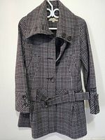 Full view of the women's plaid jacket hanging, showing single-breasted button closure and belt.