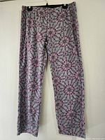 Full-length view of pajama bottoms hanging on a black clip hanger against a white wall showing the entire pattern and cut.