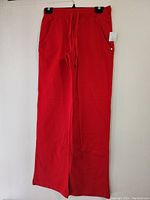 Front view of red pajama pants hanging on a hanger, showing straight leg cut and drawstring waist.