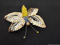Front view of butterfly pin showing detailed sequin and beadwork on wings and body.