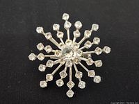 Snowflake-shaped jeweled pin front view on black background