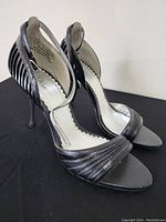 Front and side view of both black women’s high heel sandals showing open toe, ankle strap, and heel.
