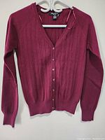 Front view of the women's red open front button-up sweater hanging on a white hanger.