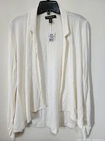 Front view of the women's ivory dressy top hanging on a black hanger, showing the flowy, draped style.