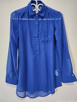 Front view of the blue silk long sleeve women's top with sheer fabric, buttoned front and chest pocket.
