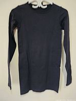 Front view of black women's long sleeve top displayed on a hanger.