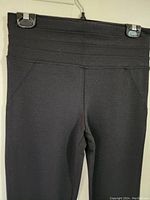 Front close-up of waistband showing horizontal ribbing and fabric texture on black stretch pants.