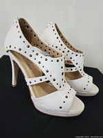Side profile of ivory open toe heels with decorative studs showing shoe shape and heel height.