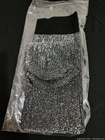 Single metallic silver sock with black cuff, in a clear plastic bag, shown folded.