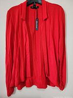 Front view of the women's red dress top on hanger showing draped collar and long sleeves.